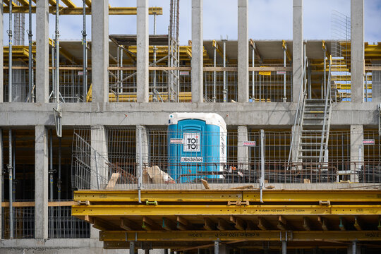 Close up of a Toi Toi portable toilet on the concrete floor of a multi-story building under construction in Gdansk, Poland.