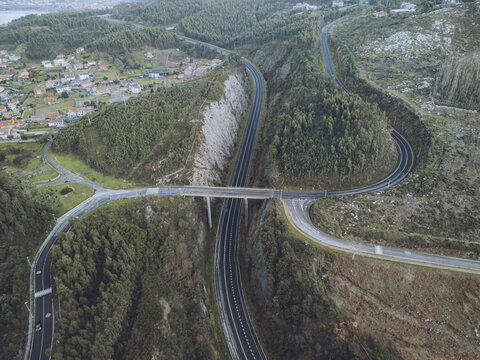Aerial view of winding Autoestrada do Val Minor amidst lush greenery and rolling hills, Baiona, Pontevedra, Spain.