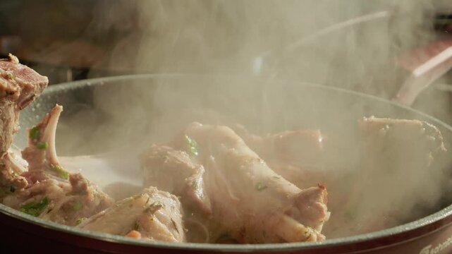 Watch as lamb is cooked in a pan with water and spices. The process shows the blending of flavors as the meat sizzles and steam rises from the pan.