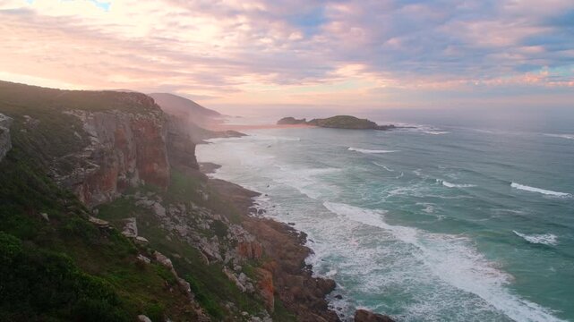 View along Robberg Nature Reserve peninsula sea cliffs with vivid sunrise clouds