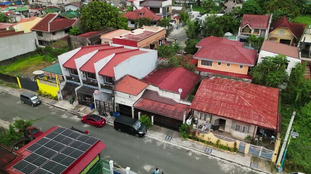 Aerial pullback of red-roofed homes line a quiet street in Broadway Pines Village, Antipolo City, Rizal, Philippines.