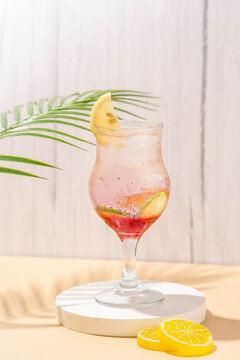 sparkling wardah non alcoholic drink served in a glass on a cream colored table with a white stone coaster, a wooden patterned background, and leaves palm as decoration.