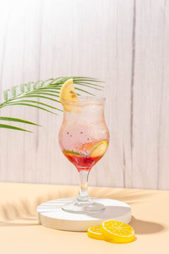 sparkling wardah non alcoholic drink served in a glass on a cream colored table with a white stone coaster, a wooden patterned background, and leaves palm as decoration.