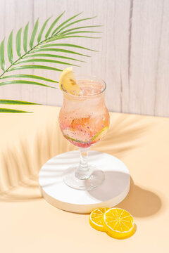 sparkling wardah non alcoholic drink served in a glass on a cream colored table with a white stone coaster, a wooden patterned background, and leaves palm as decoration.