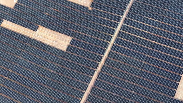 Drone aerial view of large solar panel farm under construction in arid landscape