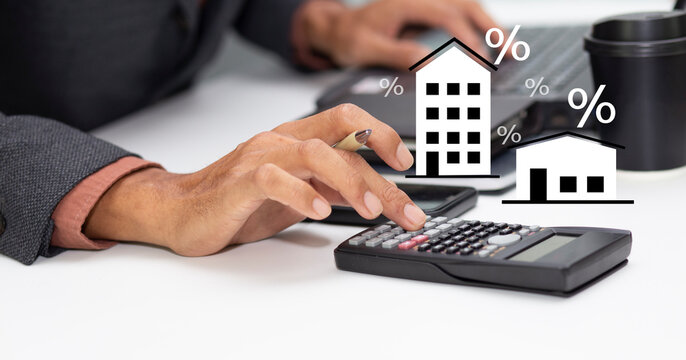 business man with calculator and calculate interest rate of condo and home, financial mortgage loan calculation, property tax, and investment