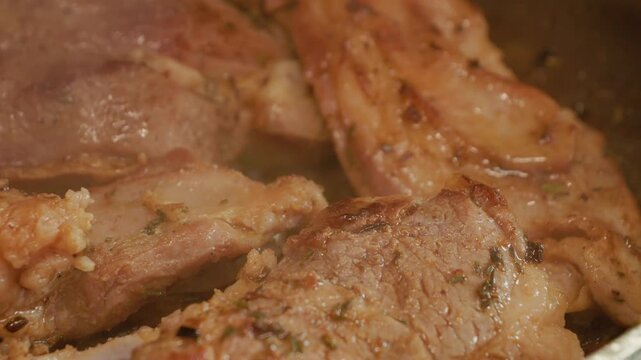 Lamb sizzles in a pan as it cooks. The meat shows juices and steam rises. The process shows the transformation from raw to cooked lamb in a kitchen setting.