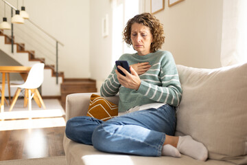 Obraz premium Woman experiencing bad news on smartphone at home