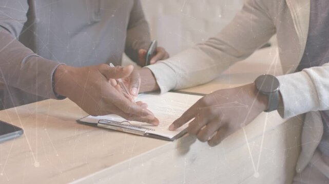 Staff guiding client at desk, pointing clipboard, handing pen while signing, completing paperwork