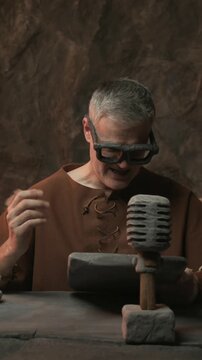 Prehistoric news presenter working in the TV studio, he is reading news and speaking into a microphone