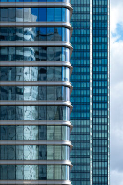 Close view of modern architecture where glass office skyscraper building facade reflection in Paris France highlights rounded corner layered levels and horizontal bands