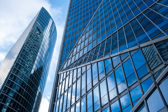 Dramatic perspective of modern architecture where glass office skyscraper building facade reflection rises in Paris France with converging towers lines and sky