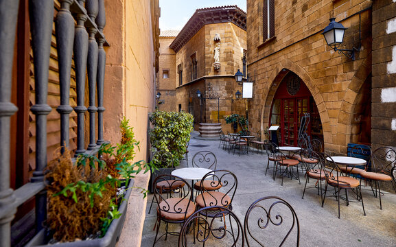 Barcelona, Catalonia, Spain. Poble Espanyol street with street cafe tables among traditional spanish gothic architecture. Gothic quarter. Narrow streets old town with medieval buildings and lanterns.