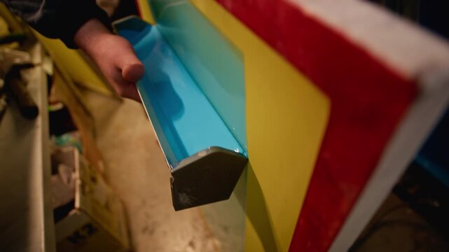 Tilt up closeup of freshly applied blue paint on metal surface with smooth glossy finish, showing branding process and coating detail