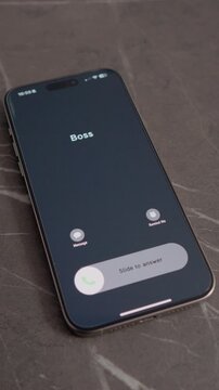 Vertical Screen: A smartphone is on a table showing an incoming call from Boss. The screen displays options to answer or decline the call. A moment of decision is taking place.