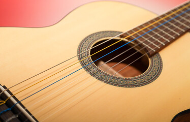 Fototapeta premium A classic light wood acoustic guitar features unique multi-colored strings, giving the instrument a vibrant and unusual look.