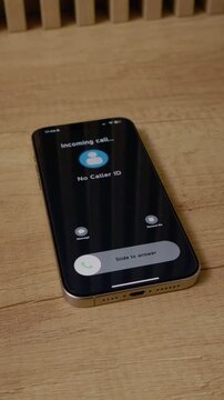 Vertical Screen: A smartphone receives an incoming call from No Caller ID while resting on a wooden table. The screen displays the call information clearly.