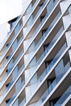 Modern apartment facade architecture with balcony glass windows and grid pattern for real estate marketing showing residential building exterior detail