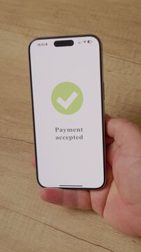 Vertical Screen: A man holds a smartphone displaying a payment accepted message. The action shows the process of making a purchase using mobile payment technology.