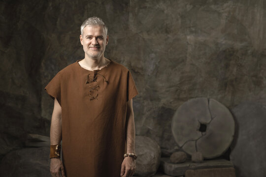 Smiling Prehistoric Caveman with Ancient Stone Wheel Invention in Cave
