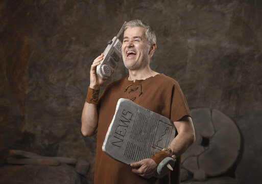 Funny Caveman Talking on Stone Mobile Phone Holding News Tablet