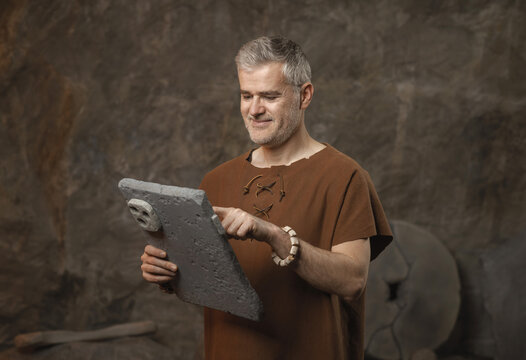 Funny Prehistoric Caveman Using a Primitive Stone Tablet - Ancient Technology and Digital Irony Concept