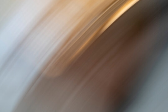 Muted earthy tones and light streaks blend in a diagonal motion blur. This abstract visualization represents economic volatility and the rapid dissemination of data in a globalized ecosystem.