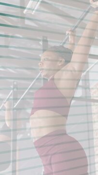 Vertical video: Right woman doing leg raises on gym pullup bar, overlay revealing body, toning core
