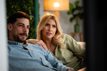 Fototapeta premium Couple relaxing together on sofa watching television