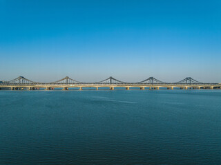 Fototapeta premium Hangzhou Qianjiang Second Bridge over calm river under blue sky