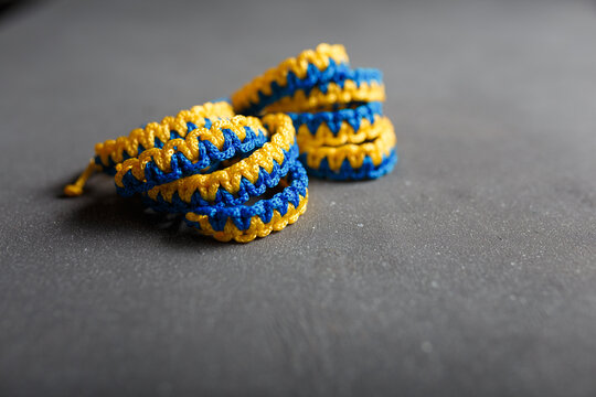 Blue yellow macrame bracelets. Wristbands in national Ukrainian flag colors on grey background. Symbol of solidarity with Ukraine. Copy space