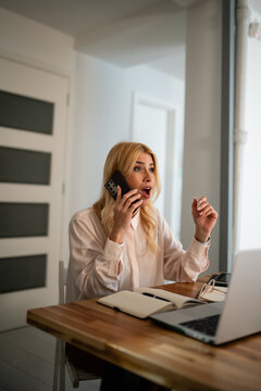 Woman receiving shocking news on phone while working