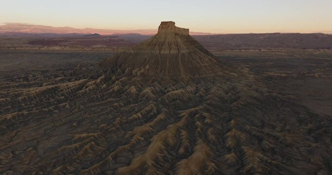 Wide aerial landscape with Factory Butte and surrounding Utah desert terrain, panoramic overview of orange glow on winding tendrils