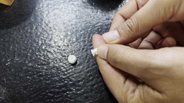 Close up of hands twisting and removing the protective cap from a sterile medical lancet for blood sugar monitoring.