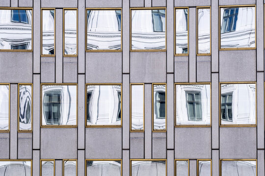 Modern architecture facade with windows where reflection adds texture to grid pattern and symmetry across a contemporary urban building exterior detail