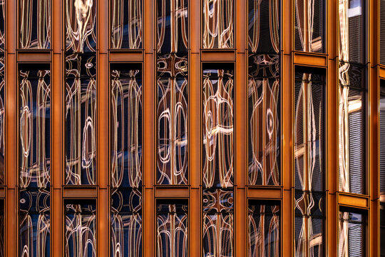 Modern architecture facade of glass building with orange reflection creating abstract pattern and distortion in contemporary urban exterior detail