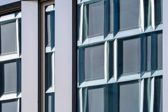 Modern architecture facade detail of glass building windows with frames where reflection forms pattern and geometry in contemporary urban exterior