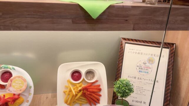Restaurant display case featuring food replicas, Japanese certificate and decorative plant.
