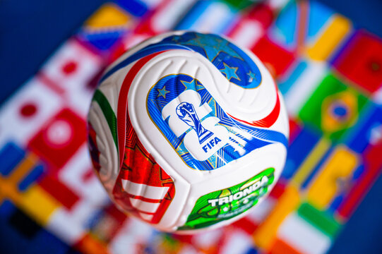 Official FIFA World Cup 2026 Match Ball Featured on Green Pitch with Blurred International Flags in Background