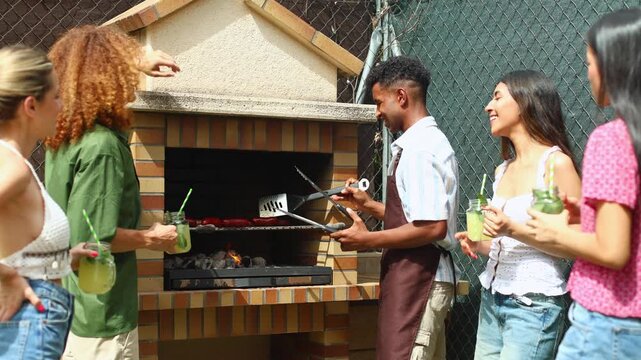 Friends grilling sausages and enjoying refreshments at backyard barbecue