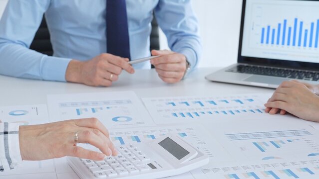 Accouters analyzing financial data using charts, graphs, and reports during an office meeting, collaborating on strategy. Business people concept