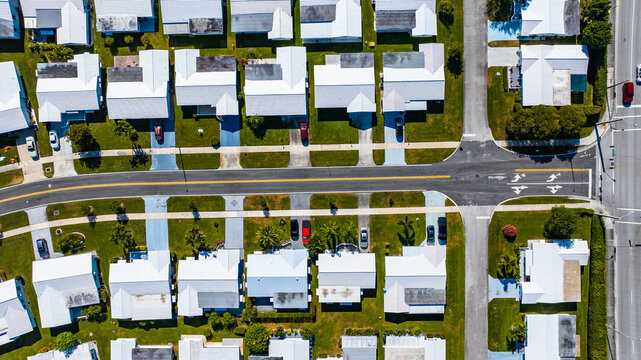 Aerial view of white-roofed homes and neat streets, a grid of suburban tranquility under the sun, with cars winding through the asphalt veins, Cape Coral, Florida, United States.