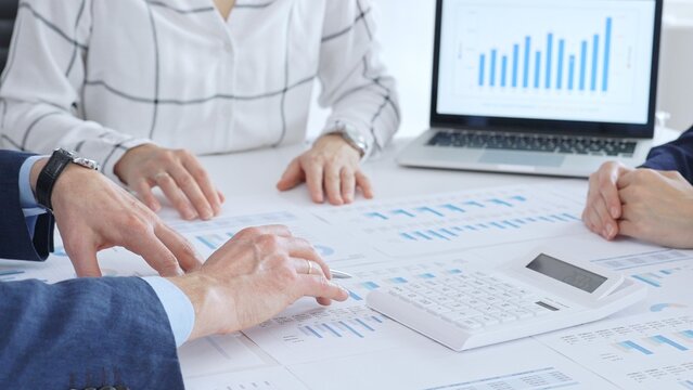Business people or accouters analyzing financial data using charts, graphs, and reports during an office meeting, collaborating on strategy