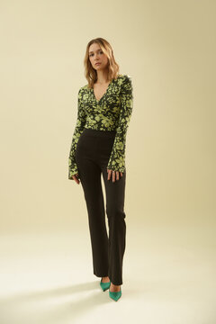 Studio Fashion Portrait of Woman in Green Floral 70s V Neck Cotton Shirt with Black Flared Pants