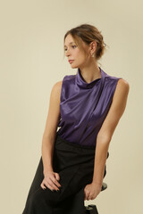 Obraz premium Studio Fashion Portrait of Woman in Purple Satin Sleeveless Draped Blouse and Black Midi A Line Skirt – Elegant Timeless Style