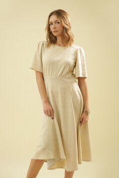 Studio Fashion Portrait of Woman in Beige Midi Short Sleeve Dress on Beige Background