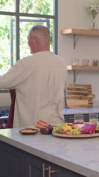 Vertical video: Turning sparking man leading woman into tender twirl in kitchen with fruit tray