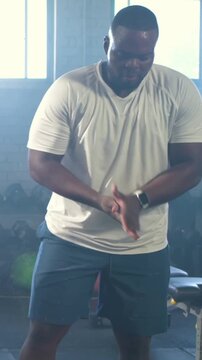 Man in white tee adjusting watch, swinging kettlebell in gym for fitness with animated counter