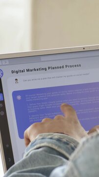 Mid-adult man touching laptop screen, tapping purple block and reviewing digital marketing plan