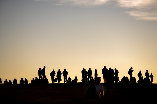 People silhouette crowd outdoors near urban skyline in Oslo Norway watching the sunset horizon with a calm shared moment